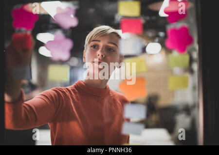 Junge Erwachsene weiblichen Brainstorming Ideen in der Nacht in einem Büro Stockfoto