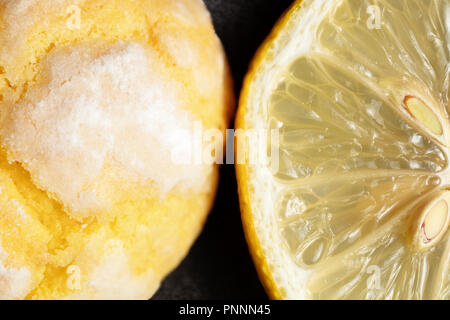 Risse crinkle Lemon cookies und Scheibe frische Zitrone auf dunklem Hintergrund. Nahaufnahme Stockfoto