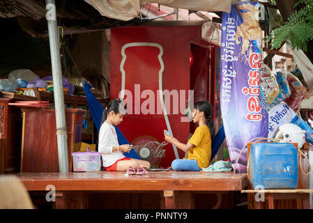 Zwei junge Mädchen, das Spiel der Karten Uno in einer Baracke durch Unordnung umgeben, in Phnom Penh, Kambodscha. Stockfoto