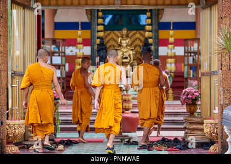 Eine Gruppe junger buddhistischer Mönche tragen orangefarbene Gewänder zu Fuß auf dem Weg zu einem Heiligtum vor dem Abendgebet in Phnom Penh, Kambodscha. Stockfoto