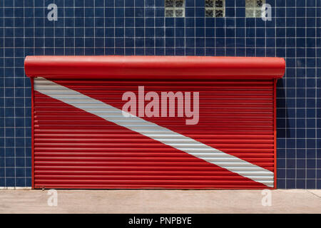 Geschlossen store Shutter auf Rot tauchen Flagge mit einer Wand mit blauen Kacheln bedeckt lackiert Stockfoto
