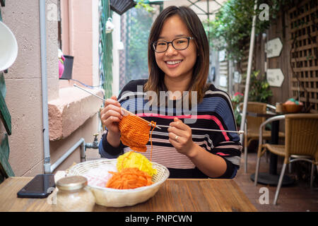 Junge Frau fröhlich Stricken im Freien Stockfoto