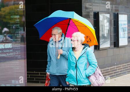 Hastings, East Sussex, UK. 22 Sep, 2018. UK Wetter: Das Wetter nimmt eine Wendung zum Schlechteren als Regen gießt unten auf dieser ältere Paare, die einen hellen und bunten Regenschirm sich von der schlechtesten des Wetters zu schützen. © Paul Lawrenson 2018, Foto: Paul Lawrenson/Alamy leben Nachrichten Stockfoto