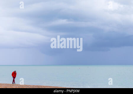 Hastings, East Sussex, UK. 22 Sep, 2018. UK Wetter: ein Mann in einer hellen roten Jacke Spaziergänge entlang der Küste von Hastings wie das Meer wird ein helles Smaragd mit schönen Wolkenbildung. © Paul Lawrenson 2018, Foto: Paul Lawrenson/Alamy leben Nachrichten Stockfoto