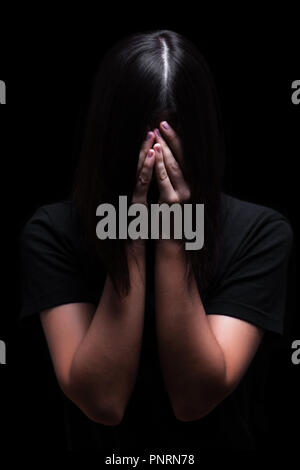 Emotionale Frau weinen und das Gesicht mit den Händen verstecken der Tränen, auf einem schwarzen oder dunklen Hintergrund. Konzept für die Opfer depression Schmerz Trauer Stockfoto