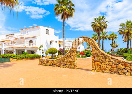 Tor zum Park und weiße Häuser mit tropischen Pflanzen in kleinen Dorf an der Küste in der Nähe von Marbella, Costa del Sol, Spanien Stockfoto