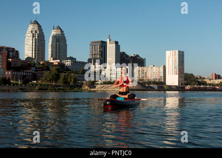 Yoga Lotus. Junge Frau Yoga am See auf einem Brett, sitzen in Lotus Stand Up Paddling Stockfoto