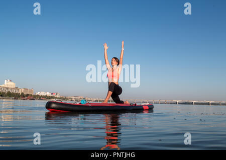 Frau Yoga auf dem sup Board mit Paddel Stockfoto