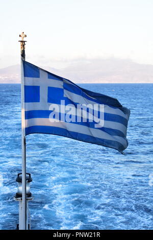 Die griechische Flagge flattert im Wind auf einer Fähre, die an einem Sommertag über die Ägäis fährt. Blauer Himmel. Blick auf Meer und Horizont. Speicherplatz kopieren Stockfoto
