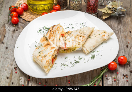 Shawarma Sandwich oder lavash mit frischem Gemüse und Sauce auf der grauen Platte decotated mit Kirschtomaten, Basilikum in der grauen Tabelle. Stockfoto