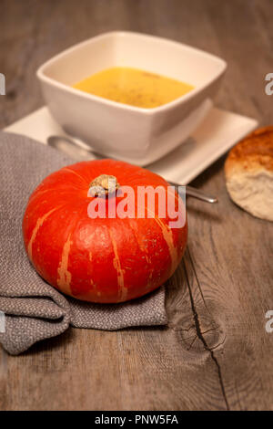 Kürbissuppe, hausgemachte Suppe auf einem rustikalen Holztisch mit Brot Stockfoto