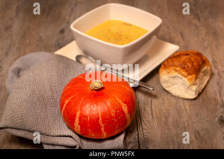 Kürbissuppe, hausgemachte Suppe auf einem rustikalen Holztisch mit Brot Stockfoto