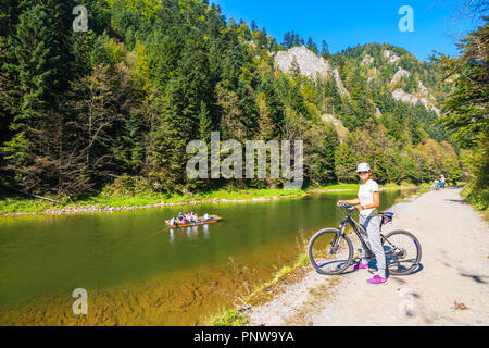 DUNAJEC, PIENINY - Sep 19, 2018: Junge Frau Radfahrer am Ufer des Flusses an sonnigen Herbsttag. Der Dunajec ist ein Fluss, der durch s Stockfoto