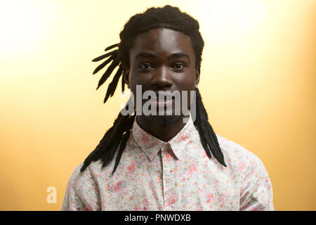 Jungen schönen afrikanischen Mann mit Blumen Shirt mit gelbem Hintergrund Stockfoto