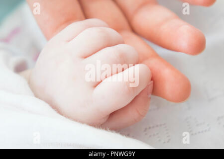 Hand des schlafenden Baby in der Hand der Mutter close-up auf dem Bett, neue Familie und Baby gesund Konzept Stockfoto