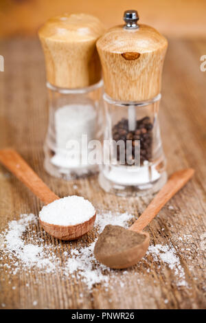 Salz und Pfeffer in der Löffel und Shaker auf rustikalen Holztisch Stockfoto