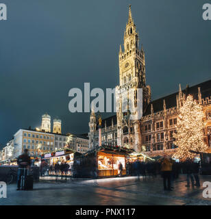 Verwischt die Menschen bewegt und Verkaufsstand auf dem Weihnachtsmarkt am Marienplatz vor dem Rathaus Neues Rathaus in München, Deutschland Stockfoto