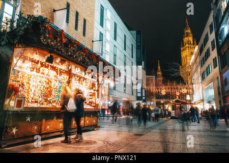 Verwischt die Menschen bewegt und Verkaufsstand auf dem Weihnachtsmarkt am Marienplatz vor dem Rathaus Neues Rathaus in München, Deutschland Stockfoto