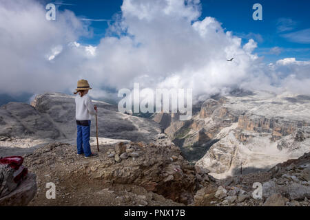 Junges Kind mit Blick auf die Landschaft auf die Sella Gruppe massiv, mit einsamen Bussard im Himmel Stockfoto