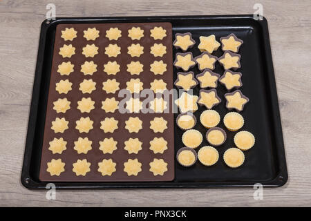 Coconut cupcakes in Silikon Formen close-up. Backformen von süßem Teig in Blume, Stern und Kreis Form gefüllt. Weihnachten und Neujahr Cookies. Stockfoto