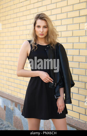 Schöne Mädchen in kurzen schwarzen Kleid und Lederjacke auf der Straße Stockfoto