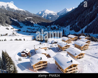 Gargellen, einem Dorf in den österreichischen Alpen, mit Schnee Chalets in den Vordergrund und die Berge im Hintergrund. Stockfoto