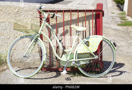 Vintage White Fahrradverleih in der Nähe ein rotes kleines Tor im Sommer geparkt Stockfoto