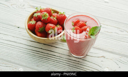 Glas mit Smoothie und Schüssel Erdbeeren Stockfoto