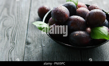 Nasse lila Pflaumen in der Schüssel Stockfoto