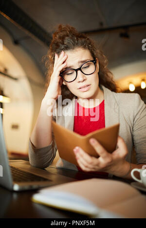 Junge Geschäftsfrau mit einem traurigen Gesichtsausdruck auf Kosten ihrer Bestellung im Restaurant Stockfoto