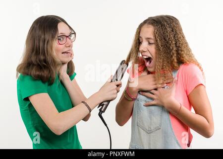 Portrait von zwei Jugendlichen Freundinnen Haarschnitt zuhause tun. Weißer Hintergrund. Stockfoto