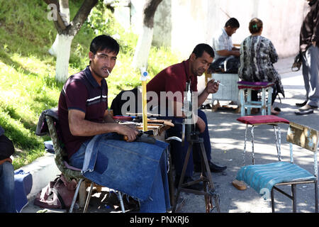 Taschkent, Usbekistan - Mai 01, 2017: Lokale Schuhmacher auf der Straßenseite stitching Hausschuhe. Stockfoto