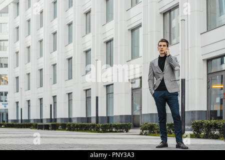 Junge Unternehmer im Gespräch per Handy neben dem Business Center. Stockfoto