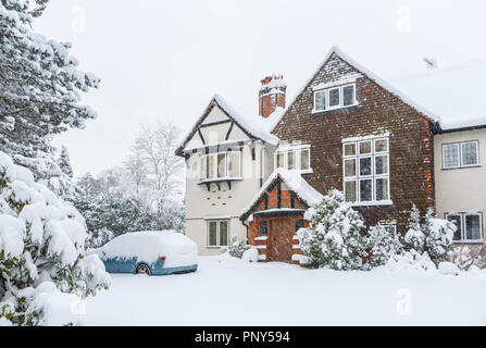 Blaues Auto in das Laufwerk eines großen Tarrant Haus in Woking, Surrey, UK abgedeckt in tiefem Schnee bei starkem Schneefall im Winter Stockfoto