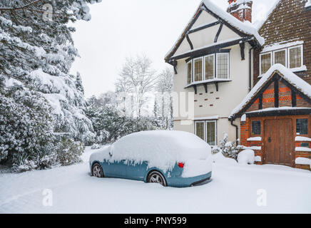 Blaues Auto in das Laufwerk eines großen Tarrant Haus in Woking, Surrey, UK abgedeckt in tiefem Schnee bei starkem Schneefall im Winter Stockfoto