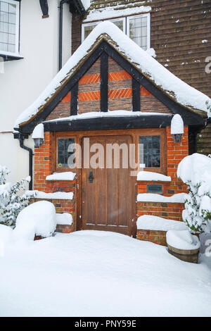 Holz Eiche Haustür und Halle ein großes Haus mit ungestörten Schneeverfrachtung bei starkem Schneefall im Winter, Woking, Surrey, Südosten, England, Grossbritannien Stockfoto