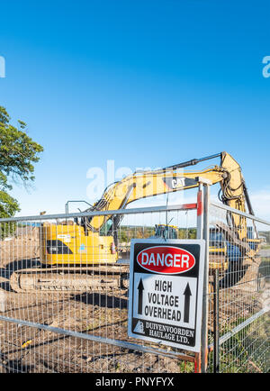 Schild an einer Baustelle Warnung Arbeitnehmer von der Anwesenheit von Hochspannung kabel Overhead. Stockfoto