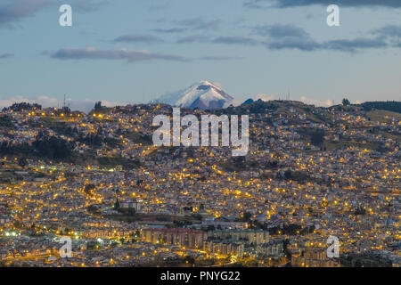 Blick auf Quito bei Nacht und den Vulkan Cotopaxi im Hintergrund, Ecuador Stockfoto