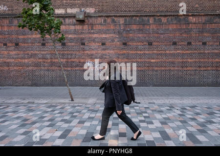 Eine einsame Person an einem einsamen Baum an einem windigen Tag in London. Stockfoto