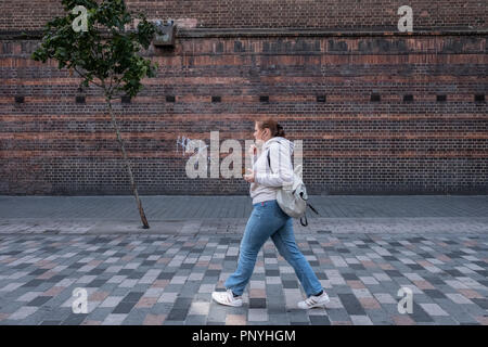 Eine einsame Person an einem einsamen Baum an einem windigen Tag in London. Stockfoto