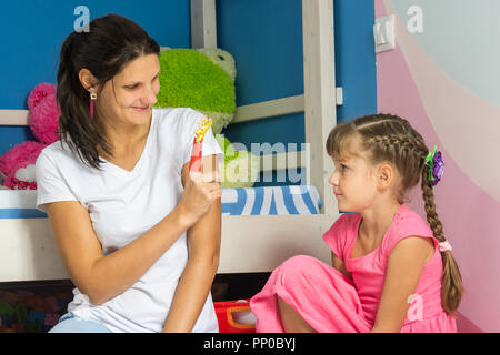 Mom eine Abbildung von farbigem Papier auf ihren Finger und zeigt ihre Tochter Stockfoto