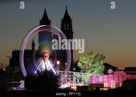 21. September 2018, Sachsen-Anhalt, Magdeburg: ein Riesenrad glänzt vor der Silhouette der Kathedrale Saint Catherine und St. Mauritius in Magdeburg an der 108 Magdeburg Herbstmesse. Bis zum 14.10.2018 können die Besucher die Meile mit Karussells und Buden auf der kleinen Stadt März jeden Tag besuchen. Foto: Peter Gercke/dpa-Zentralbild/ZB Stockfoto