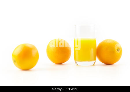 Drei Orangen und ein Glas Orangensaft auf weißem Hintergrund. Stockfoto