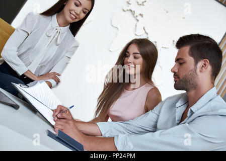 Junge paar schöne sitzend mit Manager im Reisebüro Büro- und unterzeichnen Vertrag für einen Urlaub Stockfoto