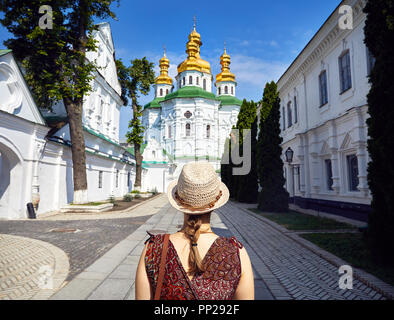 Frau mit Hut in die Kirche mit goldenen Kuppeln in Kiew Pechersk Lavra Christian komplex. Alte historische Architektur in Kiew, Ukraine Stockfoto