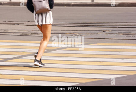 Die Beine junge Frau Überquerung einer städtischen Straße an einem sonnigen Sommertag Stockfoto