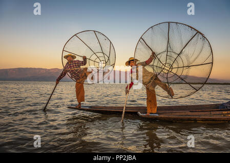 Inle See, Myanmar - Januar 28, 2016: Zwei Fischer auf traditionellen Bambus Boote stellen für Touristen mit handgefertigten Netze bei Sonnenaufgang Stockfoto