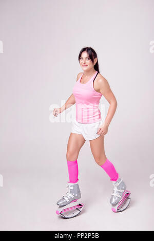 Schöne athletische Frau Tragen im Sport Style Kleidung mit Kangoo Jumps Stiefel auf ihre Beine macht Sport im Fitnessraum trainieren. Stockfoto