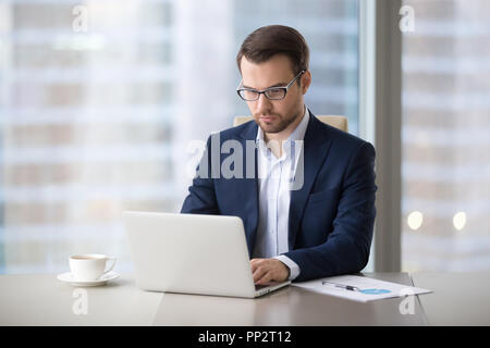 Ernsthafte Geschäftsmanns, der Eingabe von Buchstaben auf Laptop Stockfoto