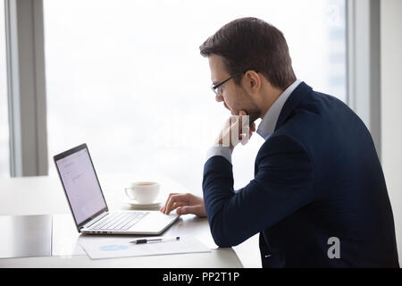 Nachdenklich Geschäftsmann, dem Schreiben von E-Mails auf Notebook Stockfoto